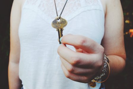 person holding gold-colored key pendant photo
