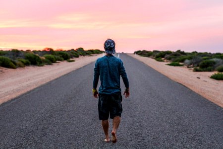 man walking on gray concrete road photo