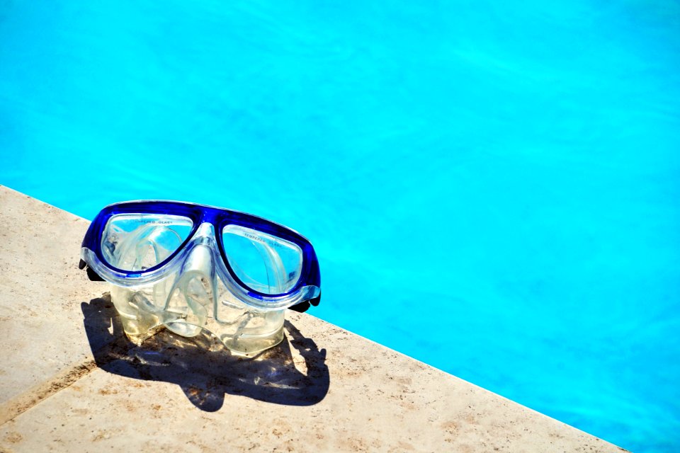 blue framed swimming goggles near pool at daytime