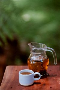 clear glass pitcher with brown liquid on brown wooden table photo