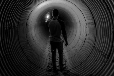 man holding light walking inside tunnel photo