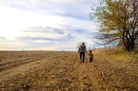 A dad walking with his kid in a field.