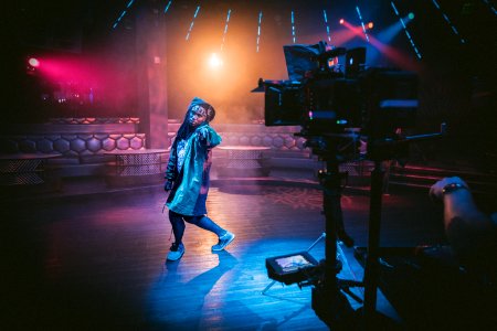 woman dancing on stage near black cameras