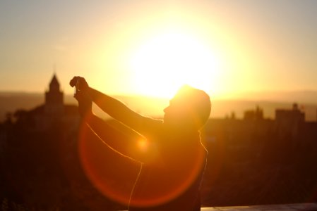 man raising hands under sunset photo