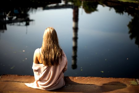 woman sitting down on porch beside body of water photo