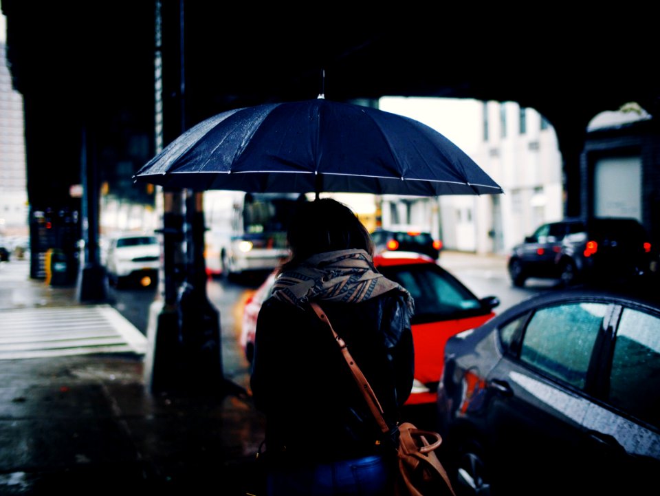 woman holding umbrella walking on street during daytime