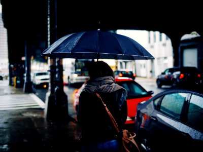 woman holding umbrella walking on street during daytime photo