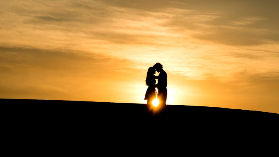 man and woman's silhouette on hill during golden hour photo