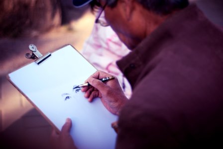 man sketching face on white printer paper photo