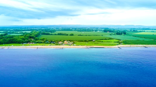 aerial photography of green fields near beach during daytime photo