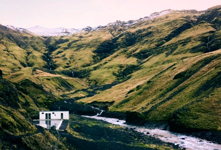 white concrete house beside body of water in the mountain photo