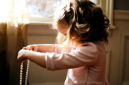 girl holding white pearl necklace inside room photo