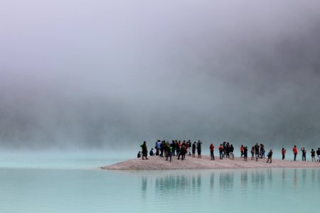 group of people standing on brown stand surrounded by body of water photo