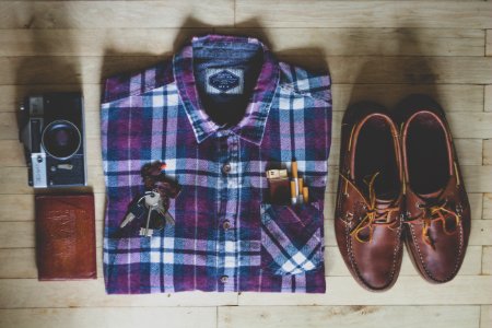 flat lay photography of button-up shirt, camera, keys, cigarettes, and pair of brown leather boat shoes photo