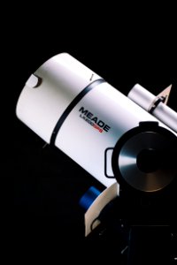 white Meade LX200GPS telescope beside black wall