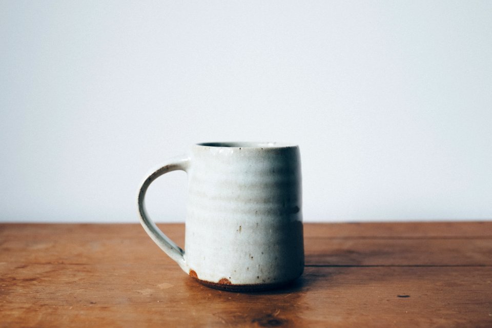 white ceramic mug on wooden table top photo
