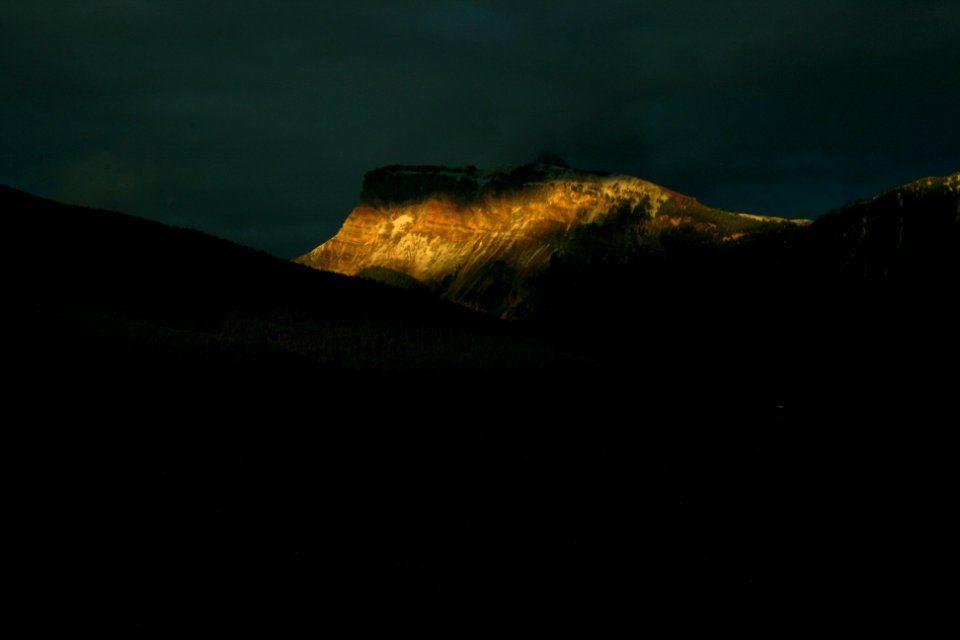 brown rock formations under nimbus clouds