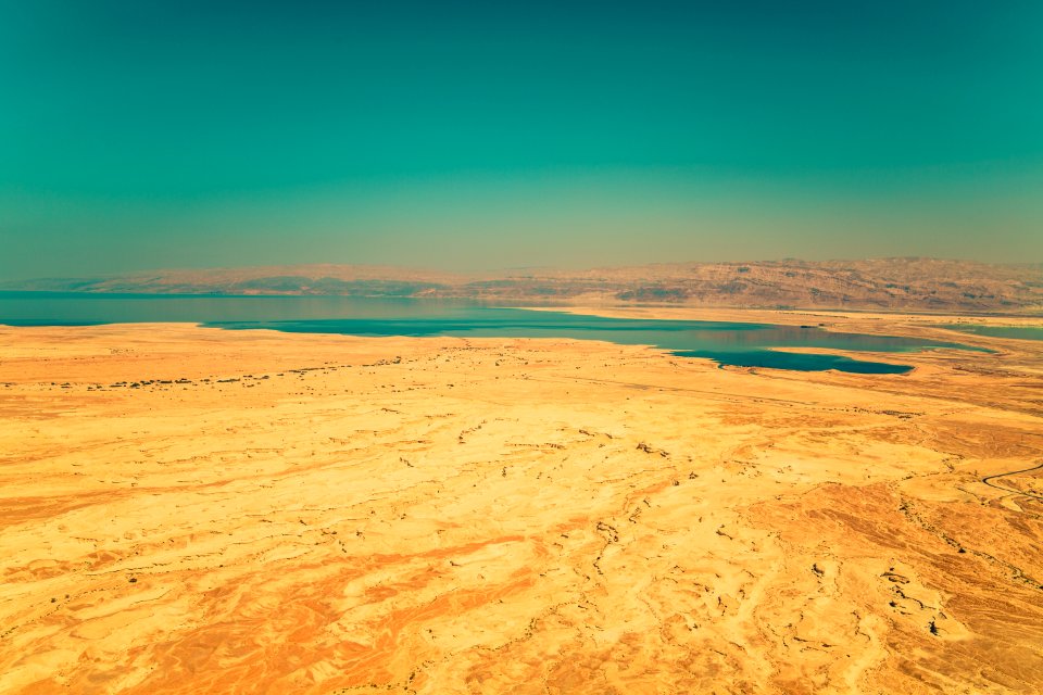 calm green sea beside brown sand under green sky