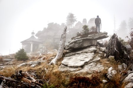 person standing on rock formation with fogs photo