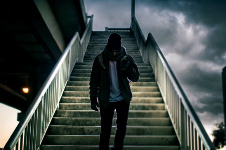man wearing brown jacket walking on the stair under black sky