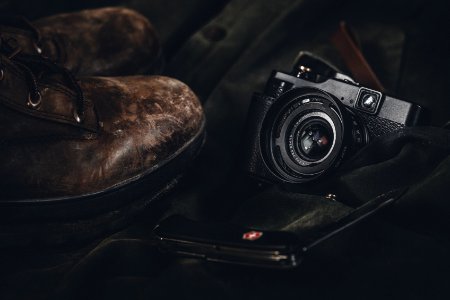 photo of a black point-and-shoot camera and pair of brown leather boots photo