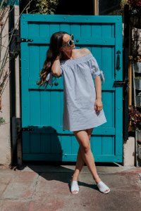 woman touching her hair standing near teal gate