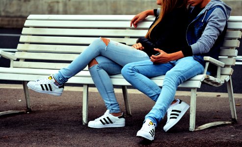 photo of couple sitting on white bench photo