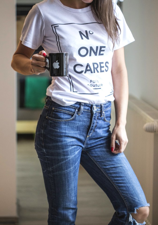 woman in white crew neck t-shirt and blue denim jeans holding black camera photo