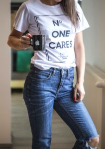woman in white crew neck t-shirt and blue denim jeans holding black camera photo