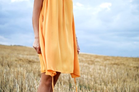 woman wearing yellow dress standing on green grass field photo