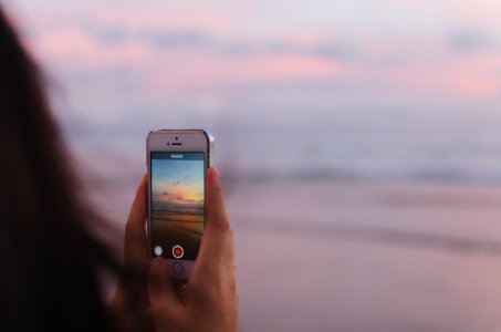 person taking a photo of of open sea and sunset photo