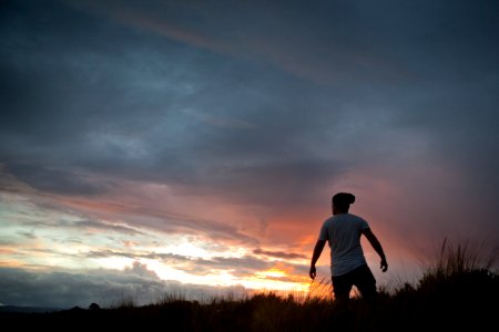 man standing on grass under white clouds