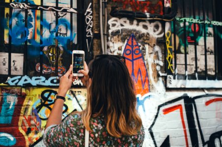 woman holding phone taking picture at wall photo