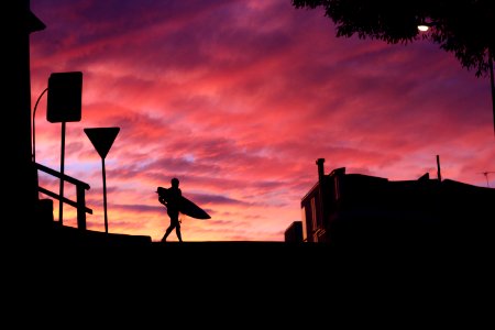 silhouette photography of man walking with a surfboard photo