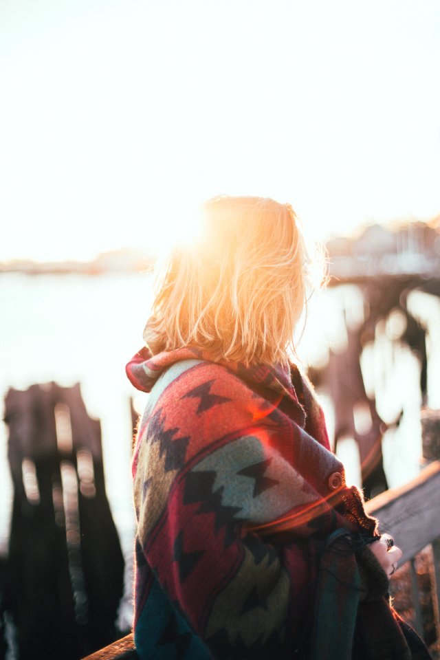 woman covered by multicolored aztec blanket