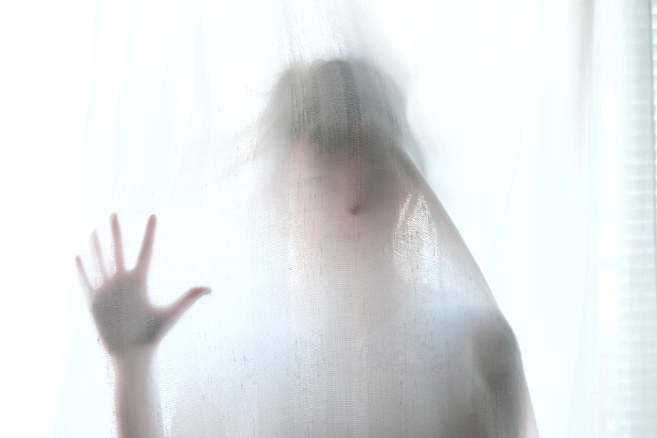 woman holding behind curtain photo