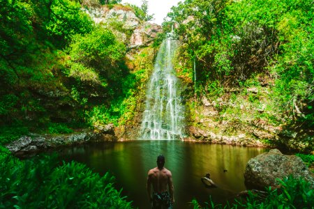 man standing in front of waterfalls during day time photo