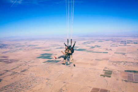 two men in 1 parachute in mid air during daytime photo