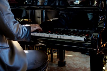 man sits on bench playing piano