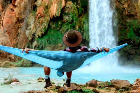 man lying on hammock near waterfalls photo