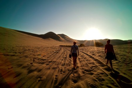 two women walking on sand during daytime photo
