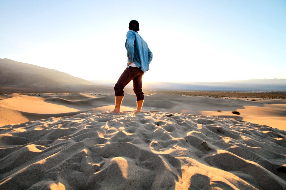 person standing at sand wearing black pants and teal jacket