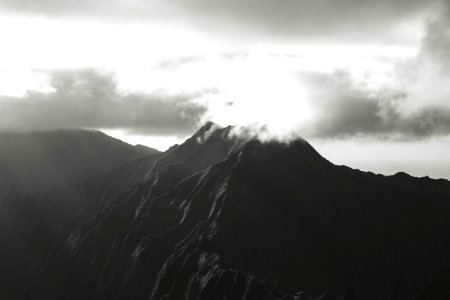 A black and white photo capturing the sun rising over a mountain in Hawaii. photo