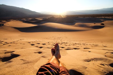 man sitting on desert during daytime photo