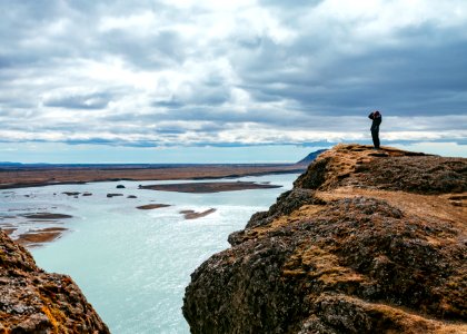 person standing on rock formation near body of water during daytime photo