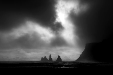 grayscale photo of rock formation surrounded by water
