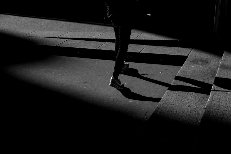 person wearing black pants and white shoes walking near gray concrete stairs