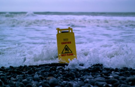 caution wet floor signage on gray rocks in seashore photo