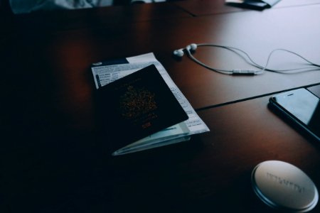 passport beside earphones on surface photo