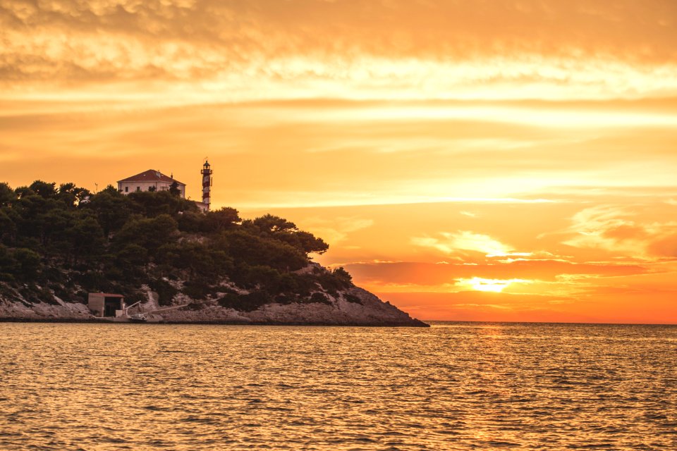 silhouette of lighthouse on top of hill during sunset